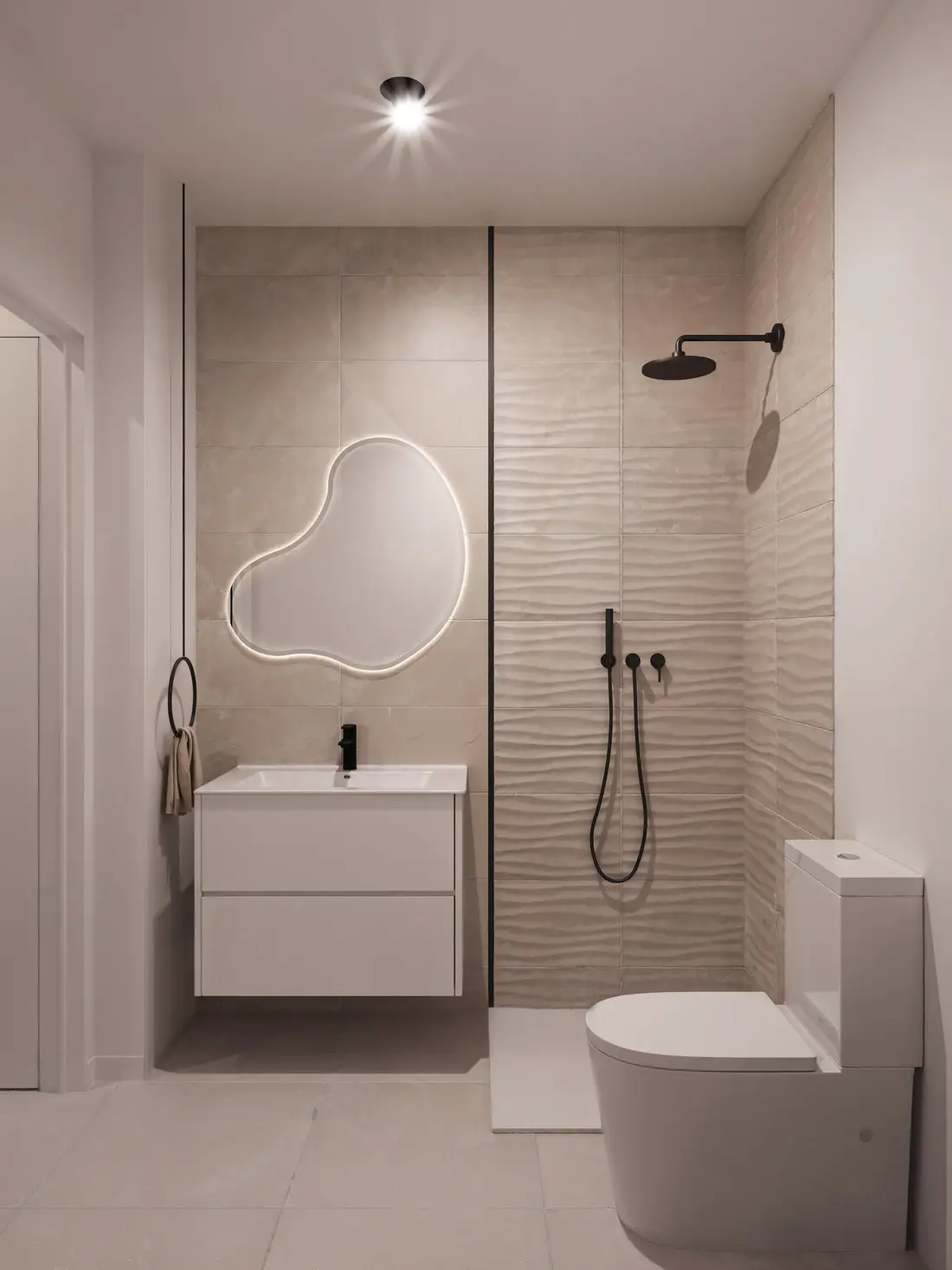 Bathroom with walk-in shower, textured porcelain tiling and a backlit organic mirror